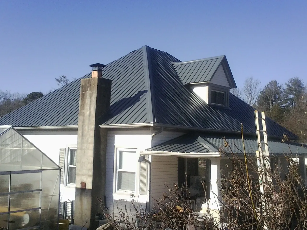 Dark blue standing seam metal roof on a white farmhouse with dormer — Slate & Tile Roof Repair by Roofing Brothers in Valley Springs