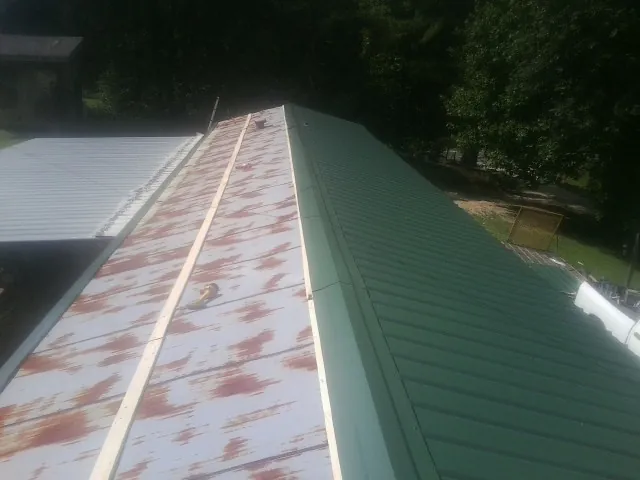 Old rusted panels beside newly installed green metal roofing — Wind Damage Roof Repair by Roofing Brothers in Valley Springs