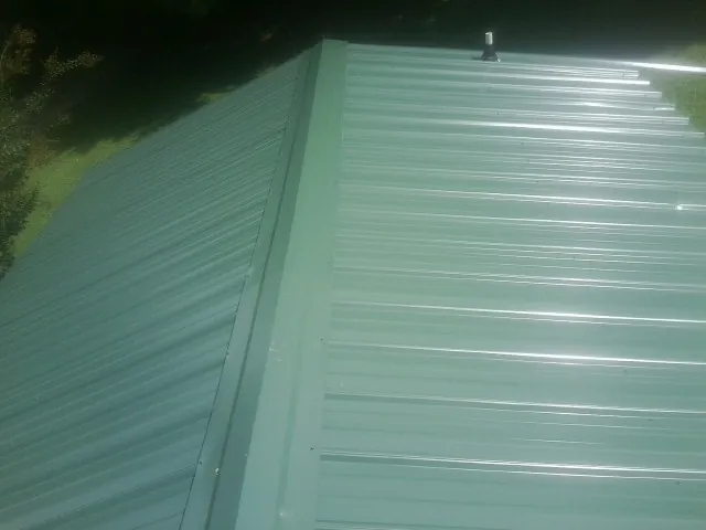 New green metal panels meeting at the ridge of a roof — Flat Roof Repair work by our crew in Valley Springs