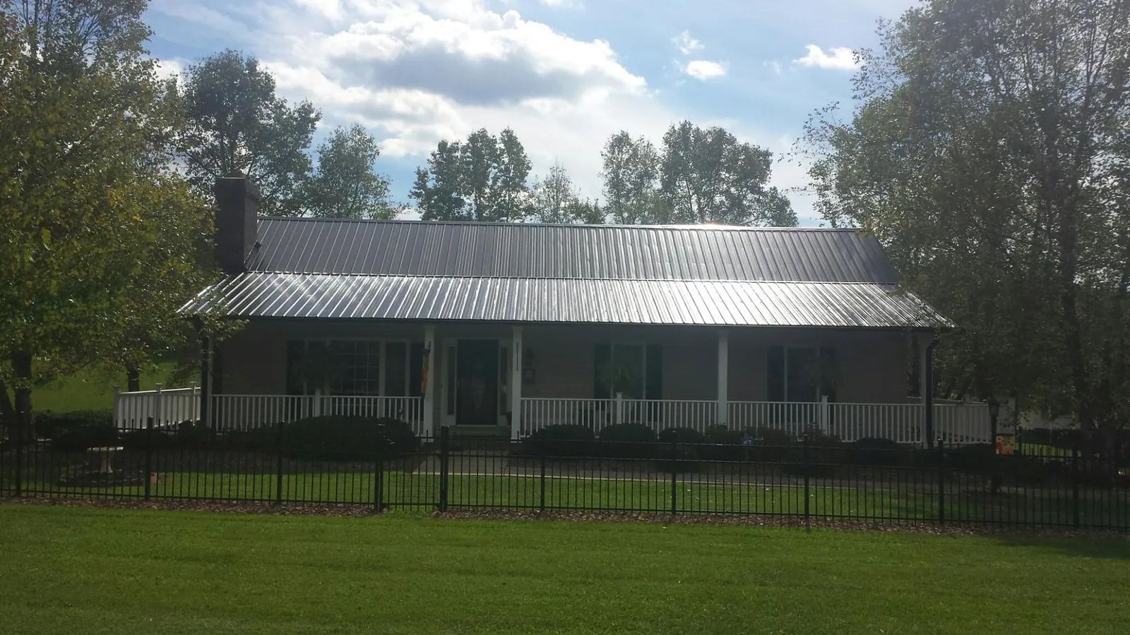 Gray metal roof on a brick ranch with a full width front porch — Gutter Guard Installation work by our crew in Valley Springs