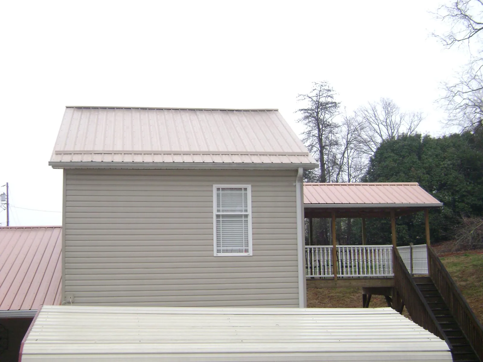 Tan metal roofs on a two story addition and attached porch, from a Roof Replacement job in Valley Springs